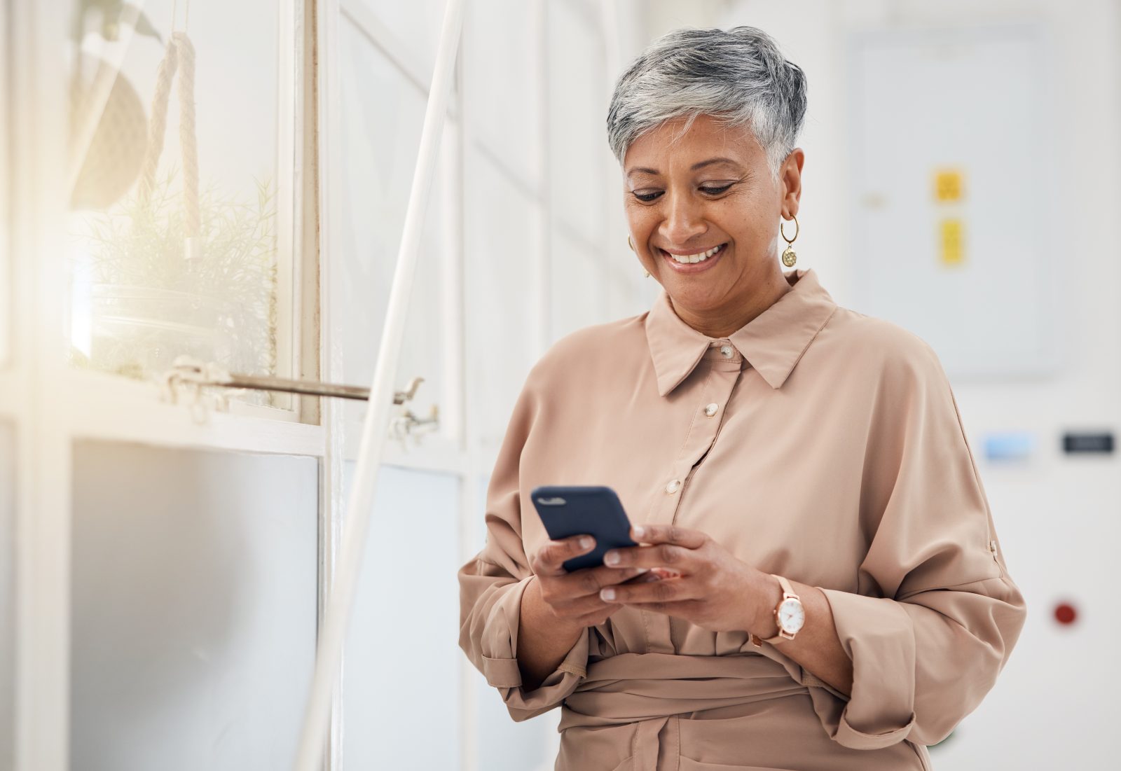 Older woman smiling while looking at her mobile phone.